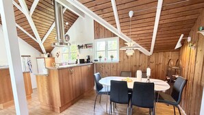 A kitchen with a central island, dining table with chairs, wooden ceiling beams, and pendant lighting. - "Gretta" - 400m from the sea by Interhome (Dannemare)