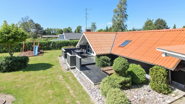 A residential property with a sloped roof, a patio area with outdoor furniture, and a well-maintained garden with trimmed bushes. - "Gretta" - 400m from the sea by Interhome (Dannemare)