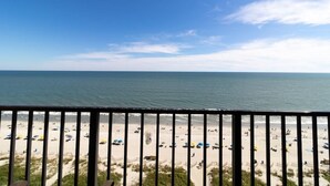 A beach view from a balcony with a railing, sandy beach, and ocean. - Nature's Front-Row: 14th Floor Palms King Suite (Myrtle Beach)