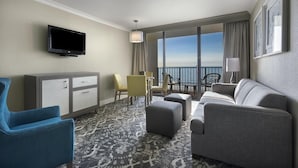 Ein Hotelzimmer mit Sofa, Sessel, Fernseher und einem Balkon mit Blick.