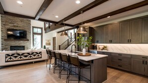 Una cocina moderna con una isla grande, armarios de madera oscura y una pared decorativa de piedra.