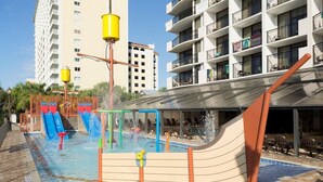 A rooftop pool area with slides and water features, surrounded by high-rise buildings. - Seaside Splendor: 2nd Floor Oceanfront Queen Suite (Myrtle Beach)