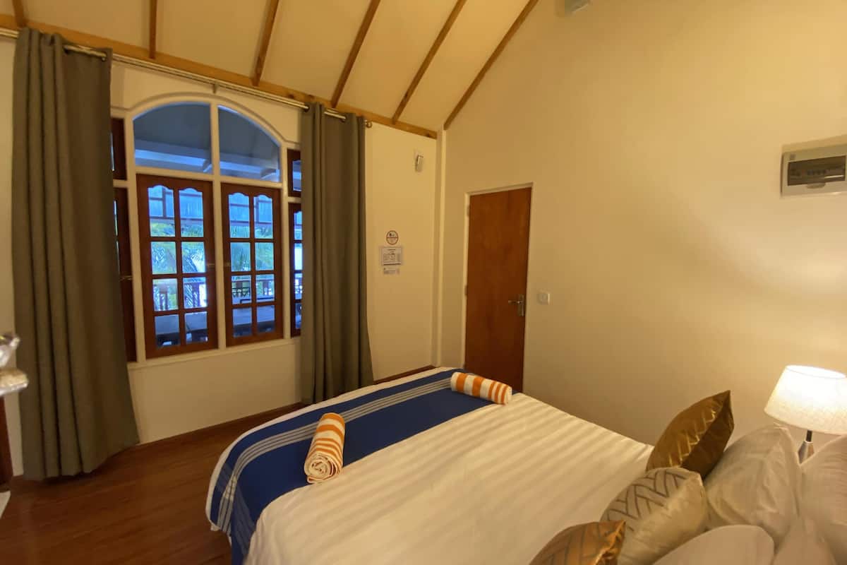 Et hotelværelse med en seng, et vindue med gardiner, en dør og en lampe.