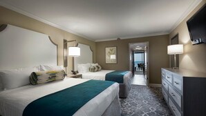 A hotel room with two beds, a desk, a dresser, and a TV. - Seaside Splendor: 4th Floor Palms Queen Suite (Myrtle Beach)