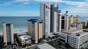 A hotel with multiple high-rise buildings, a beach view, and a parking area. - Seaside Splendor: 4th Floor Palms Queen Suite (Myrtle Beach)