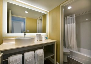 Une salle de bain équipée d’un lavabo, d’un miroir, d’un porte-serviettes et d’un espace douche.