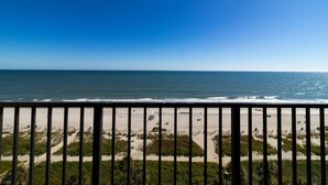 A beach view with a railing, sandy beach, and ocean. - Seaside Splendor: 8th Floor Palms Queen Suite (Myrtle Beach)