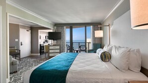 A hotel room with a bed, a desk, a television, and a view of the ocean. - Romantic Retreat: Palms King Spa Suite 8th Floor (Myrtle Beach)