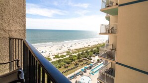 A balcony with a view of a beach and a pool area. - Seaside Serenity : 10th Floor Palms Ocean View (Myrtle Beach)