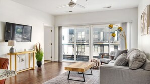 A modern living room with a wooden coffee table, grey sofa, and a TV mounted on the wall. - Stunning 1 Bedroom Luxury unit with a Pool (Columbus)