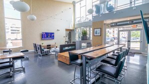 Un espace intérieur moderne doté de hauts plafonds, de grandes fenêtres et d’un agencement varié comprenant des tables et des chaises.