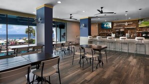 En moderne restaurant med trægulv, barområde og store vinduer der ud til stranden.