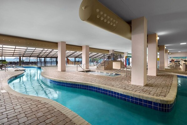 An indoor swimming pool with clear blue water, tiled edges, and a sunroof.