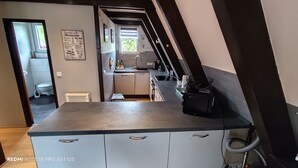 A compact kitchen with a black countertop, white cabinets, and a window above the sink. - Modernes Nurdachhaus in Fedderwardersiel für bis zu 5 Personen und Hund (Butjadingen)