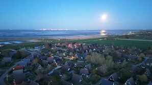 An aerial view of a coastal residential area with houses, roads, and a beach. - Modernes Nurdachhaus in Fedderwardersiel für bis zu 5 Personen und Hund (Butjadingen)