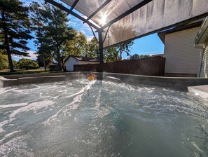Una piscina amb una font d'aigua, envoltada d'una zona coberta i arbres.