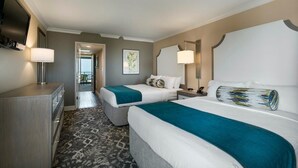 Habitación de hotel con dos camas, un escritorio, una silla, un televisor y vista al exterior.