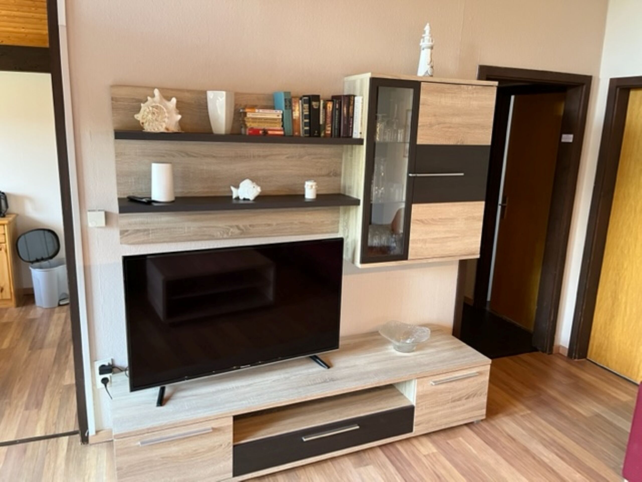 Un mueble moderno de entretenimiento con televisor, repisas y un pequeño armario.