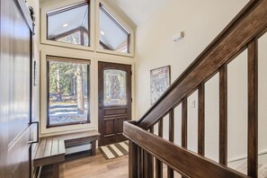 Una escalera de madera con barandilla, un banco y una puerta con un vitral.