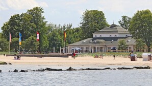 Ein Gebäude direkt am Strand mit einer Kuppel, umgeben von Flaggen und Bäumen.