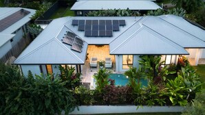 Ein modernes Haus mit Solaranlage, Schwimmbad und üppiger Bepflanzung.