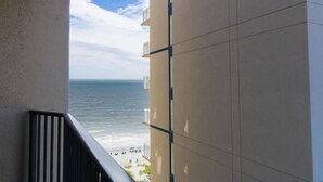 Uitzicht op een strand vanaf een balkon, met een heldere lucht.