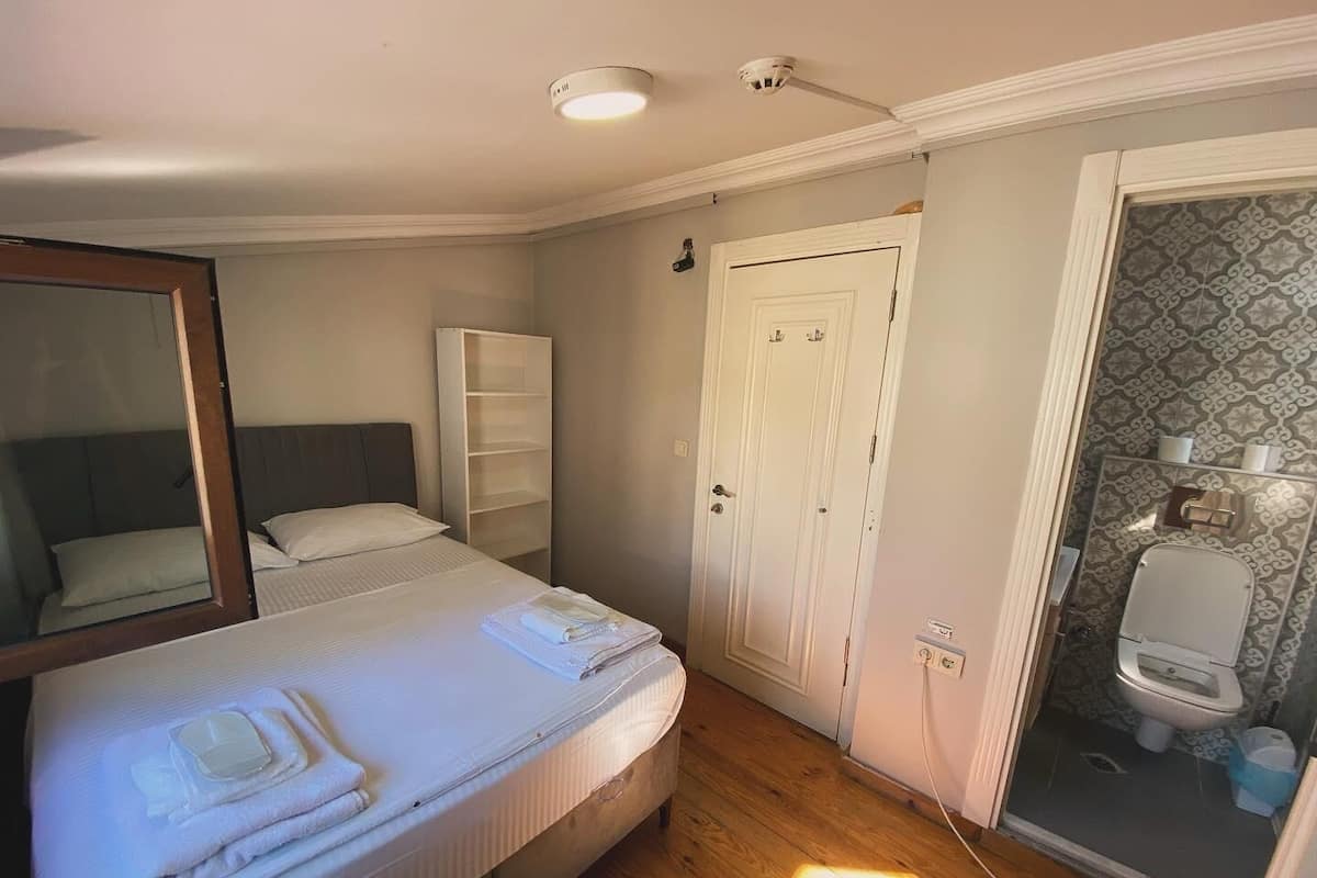 A bedroom with a bed, a wardrobe, a door, and a bathroom with a toilet.