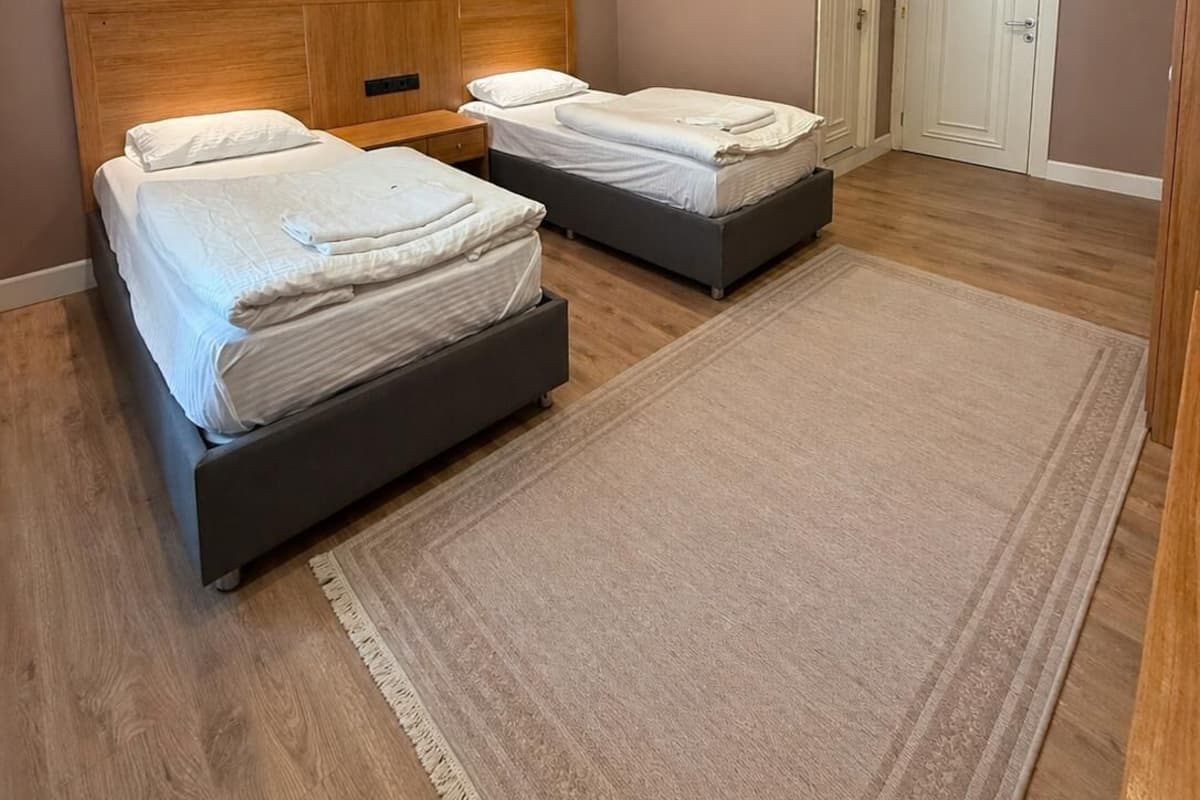 A bedroom with two beds, a wooden headboard, a white door, and a ceiling-mounted air conditioner.