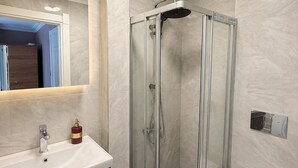 A modern bathroom with a glass-enclosed shower, a white sink with a mirror above, and a toilet. - Beşiktaş Çarşı Pansiyon (Istanbul)