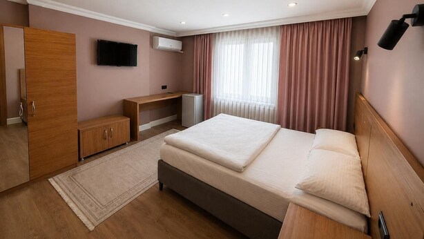 A hotel room with a bed, a desk, a wardrobe, a television, and an air conditioning unit. - Beşiktaş Çarşı Pansiyon (Istanbul)