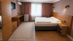 A hotel room with a bed, a desk, a wardrobe, a TV, and a radiator. - Beşiktaş Çarşı Pansiyon (Istanbul)