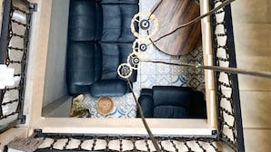Un salon moderne avec un canapé en cuir noir, un tapis à motifs et une table basse ronde originale.