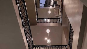 Un intérieur à plusieurs niveaux, doté d’un escalier central, d’un luminaire au plafond et d’une rampe décorative.