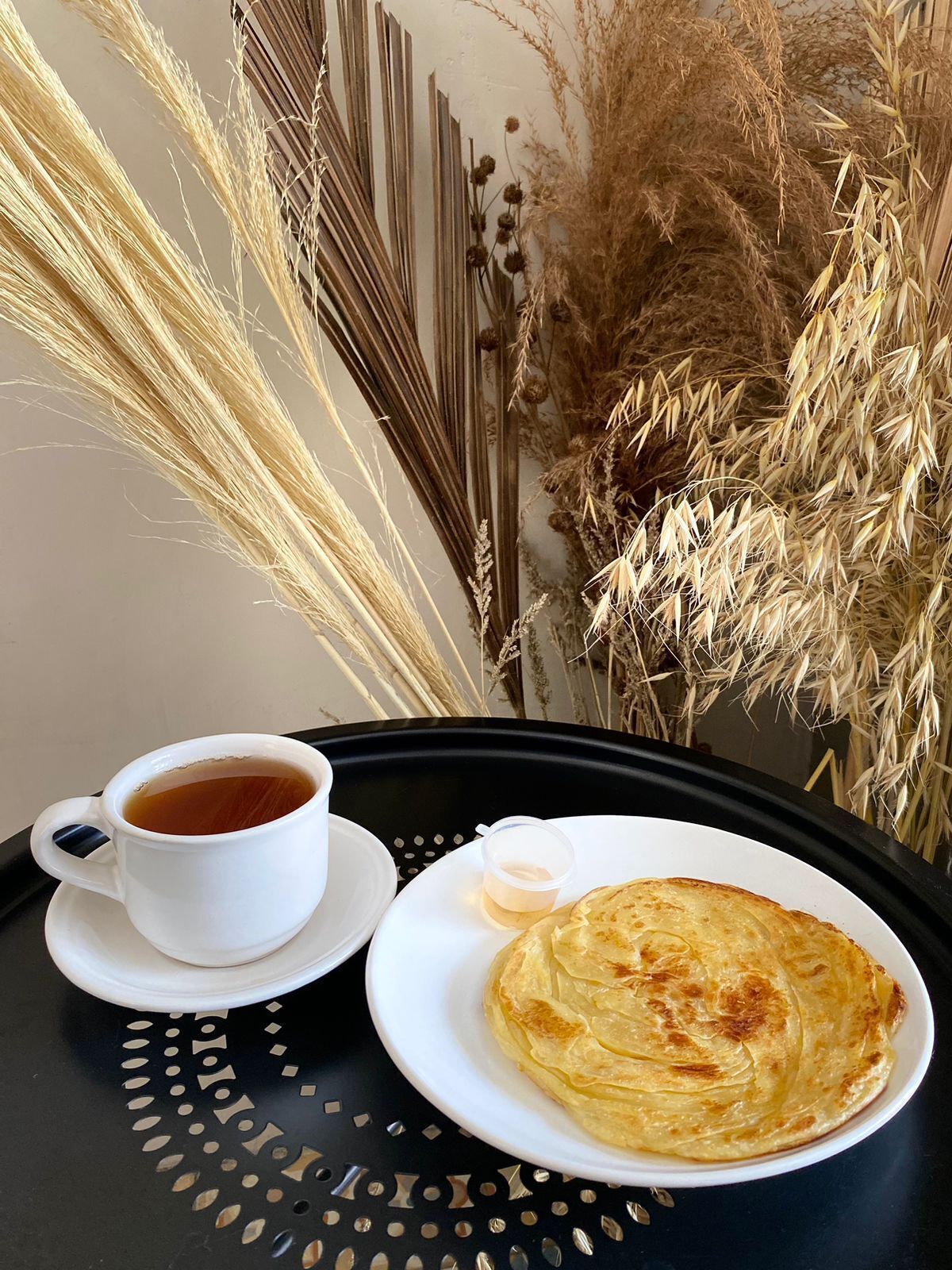 A tray with a cup of tea and a plate of pancakes.