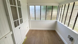 A room with wooden flooring, white walls, and a large window with blinds.