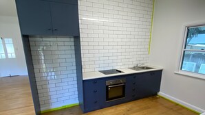 A kitchen with white and blue cabinetry, a built-in oven, and a window.