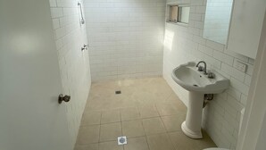 A small, clean bathroom with white tiles, a sink, a toilet, and a skylight.