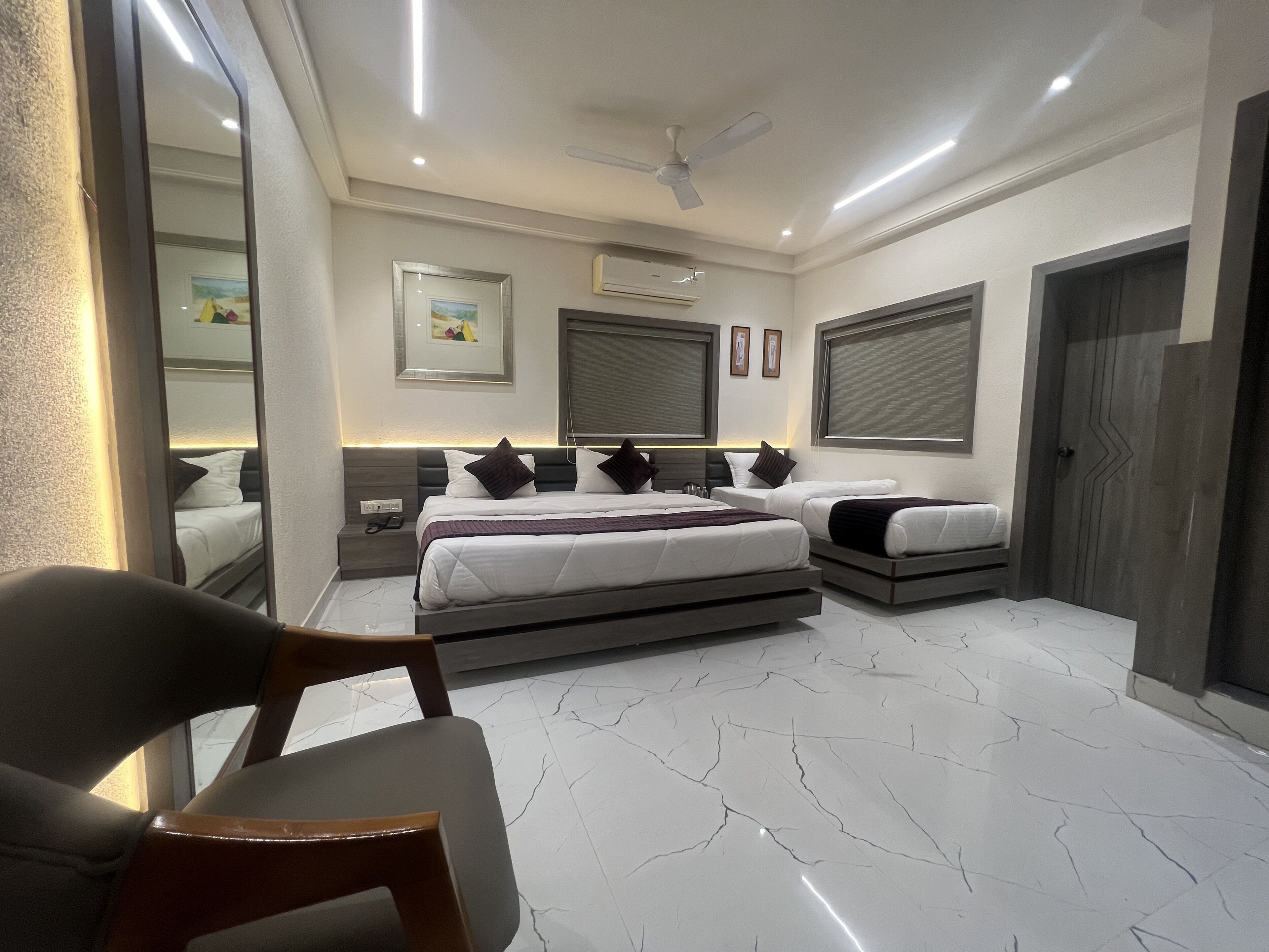 A modern bedroom with a large bed, bedside tables, a ceiling fan, and a large window with blinds.