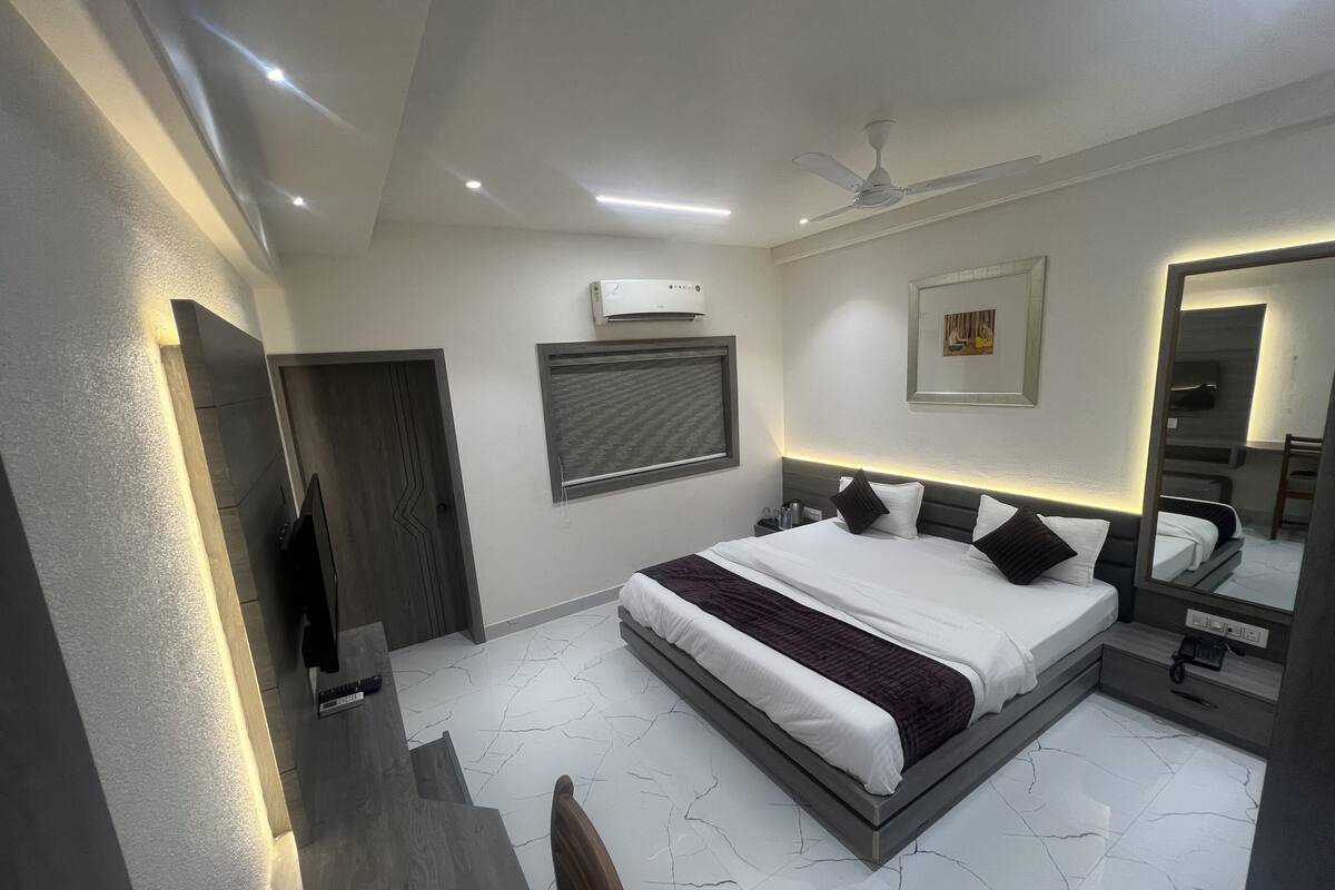 Un dormitorio moderno con una cama grande, ventilador de techo, aire acondicionado y espejo.