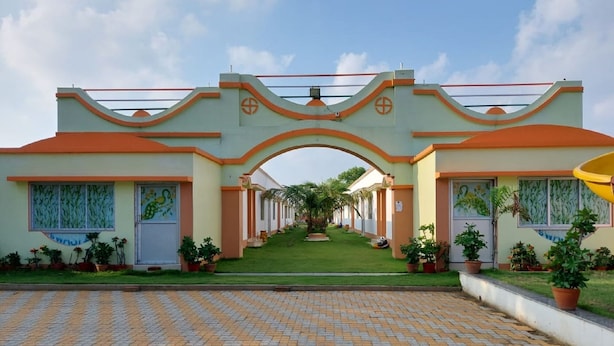 A hotel entrance with a tiled driveway leading to a covered walkway. - Swastik Resort (Kanthi)