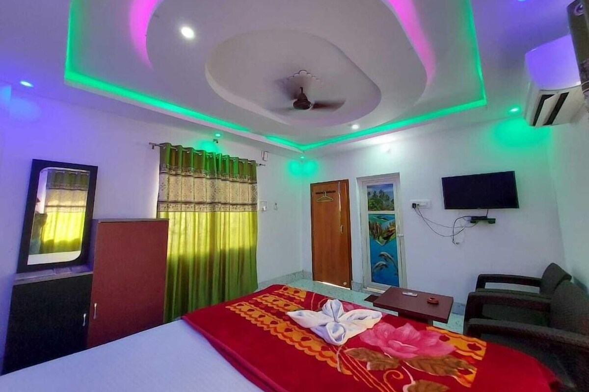 A hotel room with a bed, a desk, a chair, a TV, and a ceiling fan.