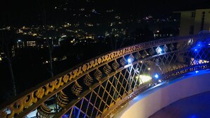 A night view of a cityscape with a brightly lit bridge featuring ornate metal railings and blue lighting. - Shreshtam Lakhnpal Resort (Manali)