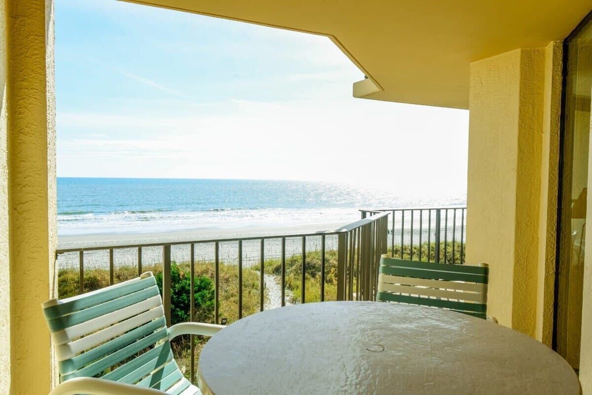 A balcony with a view of the beach and ocean.