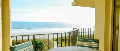 A balcony with a view of the beach and ocean.