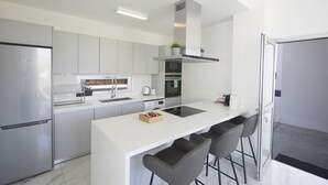 Une cuisine moderne dotée d’un îlot central, d’appareils électroménagers en acier inoxydable et de tabourets de bar.