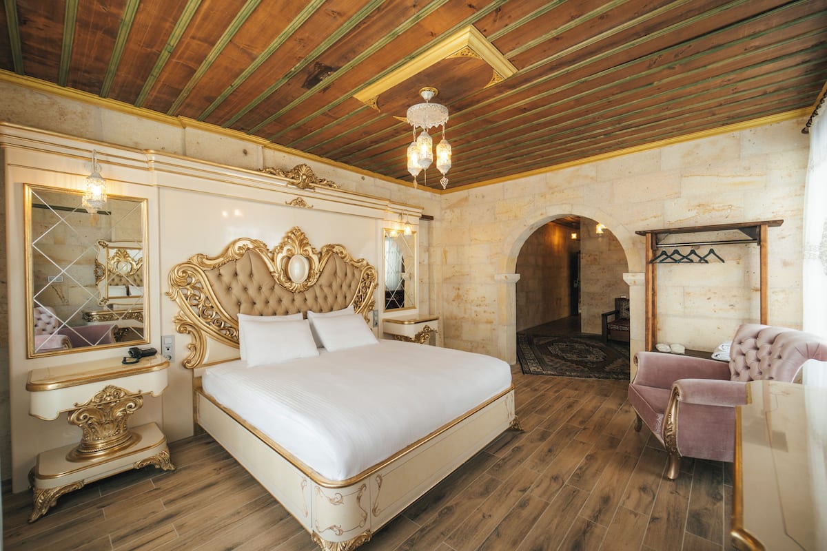 A luxurious bedroom with a large bed, ornate headboard, and a chandelier.