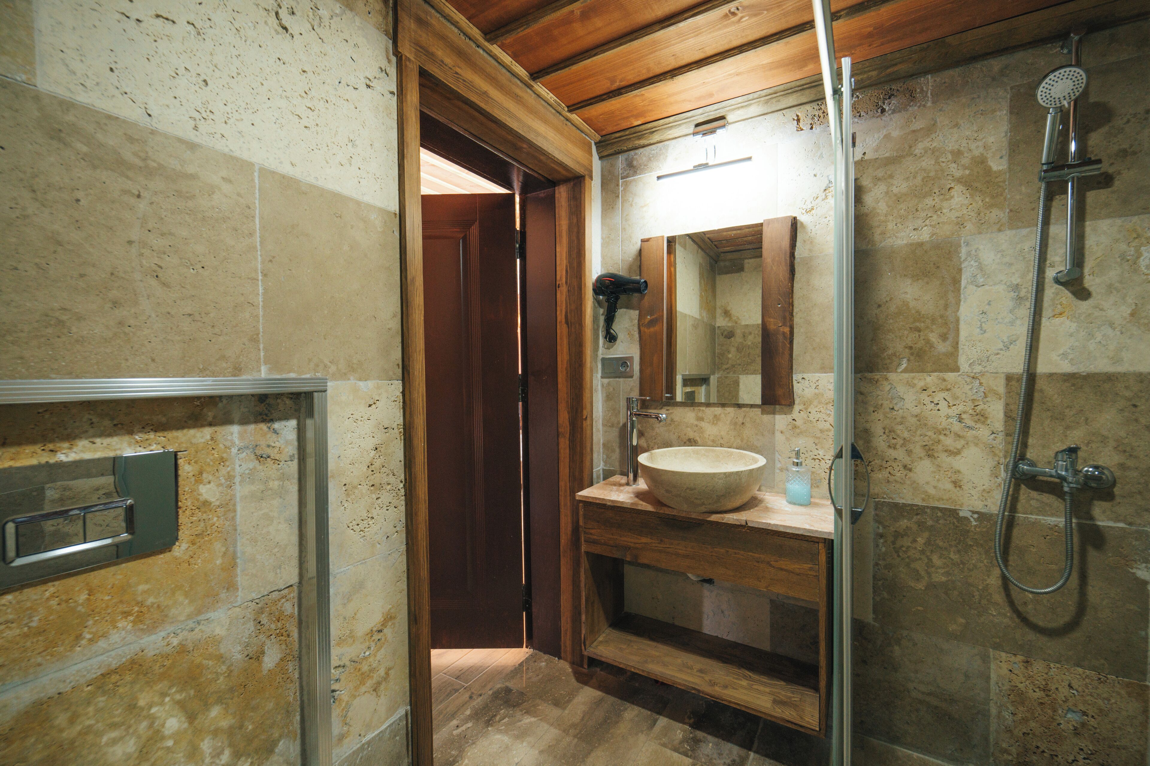 A bathroom with a wooden vanity, a large mirror, a sink, and a shower.