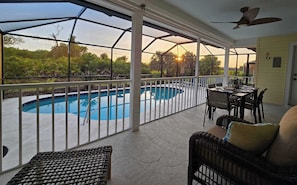 Un patio cubierto con piscina, mobiliario exterior y zona de comedor.