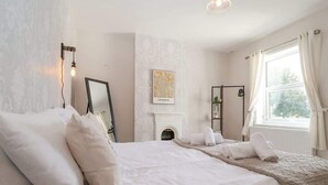 Ein Schlafzimmer mit einem großen Bett, einem Kamin, einer Karte an der Wand und einem Fenster mit Vorhängen.