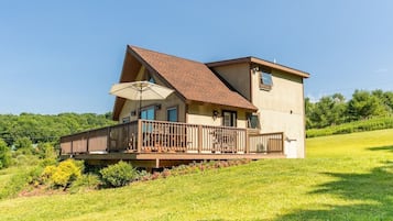 Situated on a grassy hill, this cabin offers a tranquil retreat with a balcony and lush green surroundings.